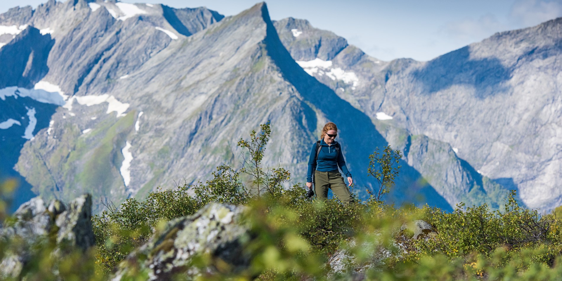 Girl hiking in Hjørundfjorden, Norway. She is surrounded by high mountain peaks