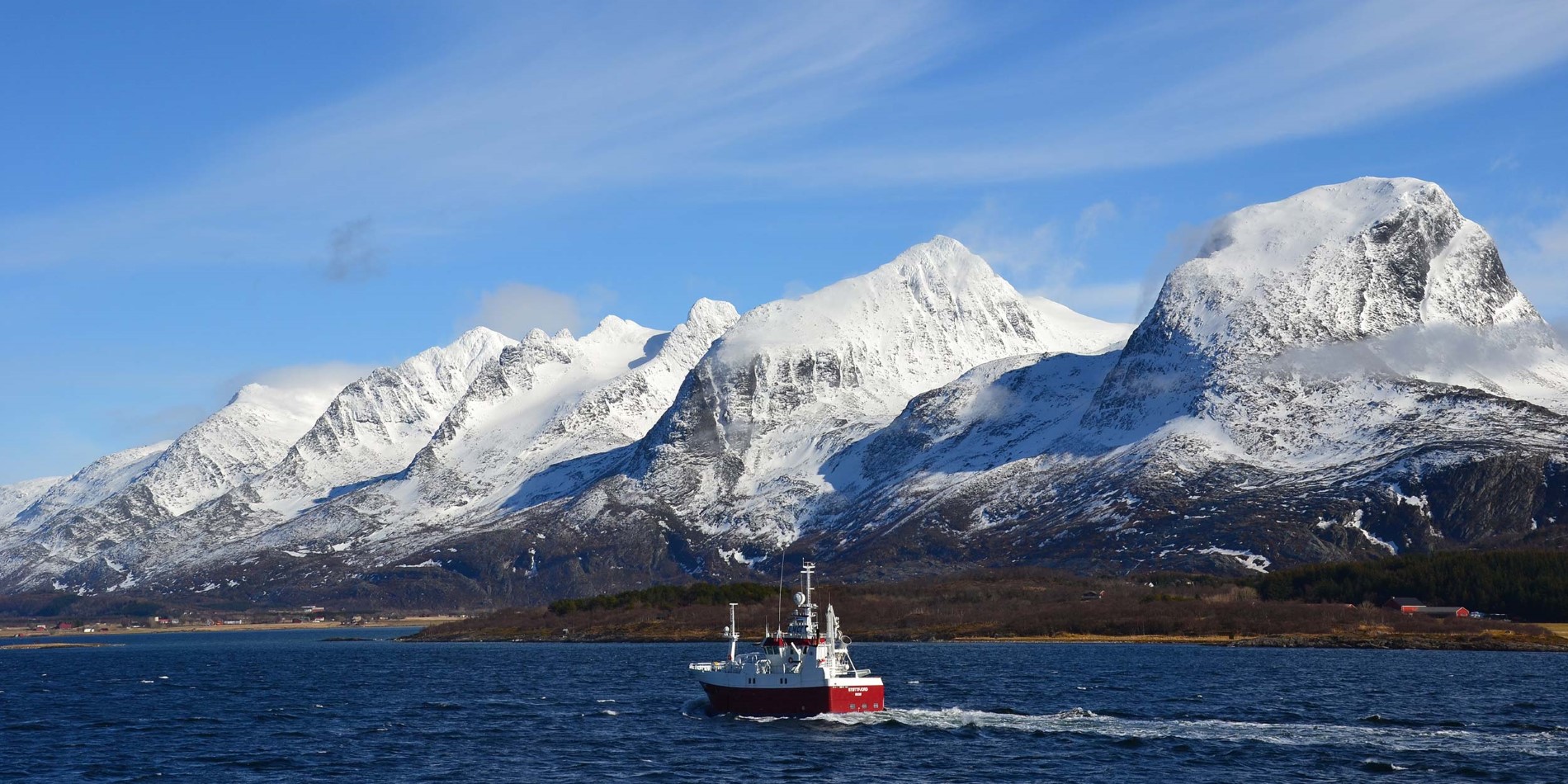 A fishing boat in front of the Seven Sisters mountain chain